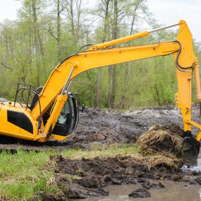 Excavator picks up big amount of soil for construction irrigation system canal in countryside for watering Excavator picks up big amount of soil for construction irrigation system canal in countryside for watering